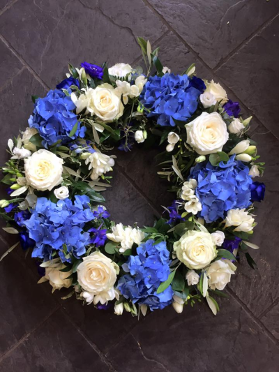 Wreath SYM-316 - A beautiful classic wreath arranged using purple and white flowers and finished with fine foliage. Wreath SYM-316 - A beautiful classic wreath arranged using purple and white flowers and finished with fine foliage.